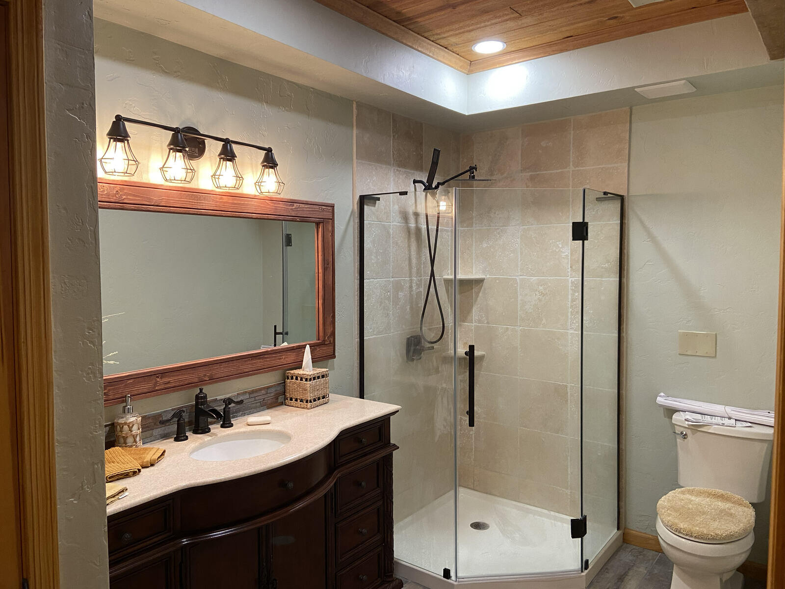 A modern bathroom with a tiled walk-in shower and wood-accented mirror by Crosby Home Services in Prescott, AZ