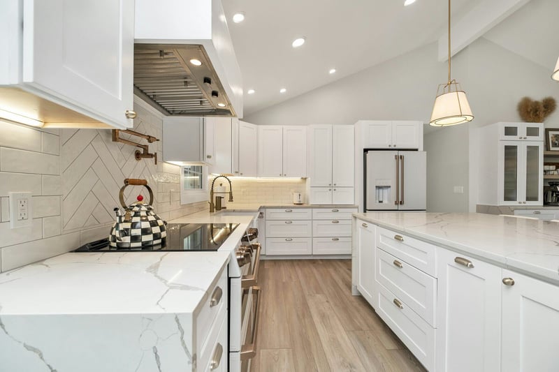 Elegant white kitchen remodel featuring a marble countertop island, gold accents, and modern finishes by Crosby Home Services in Prescott, AZ