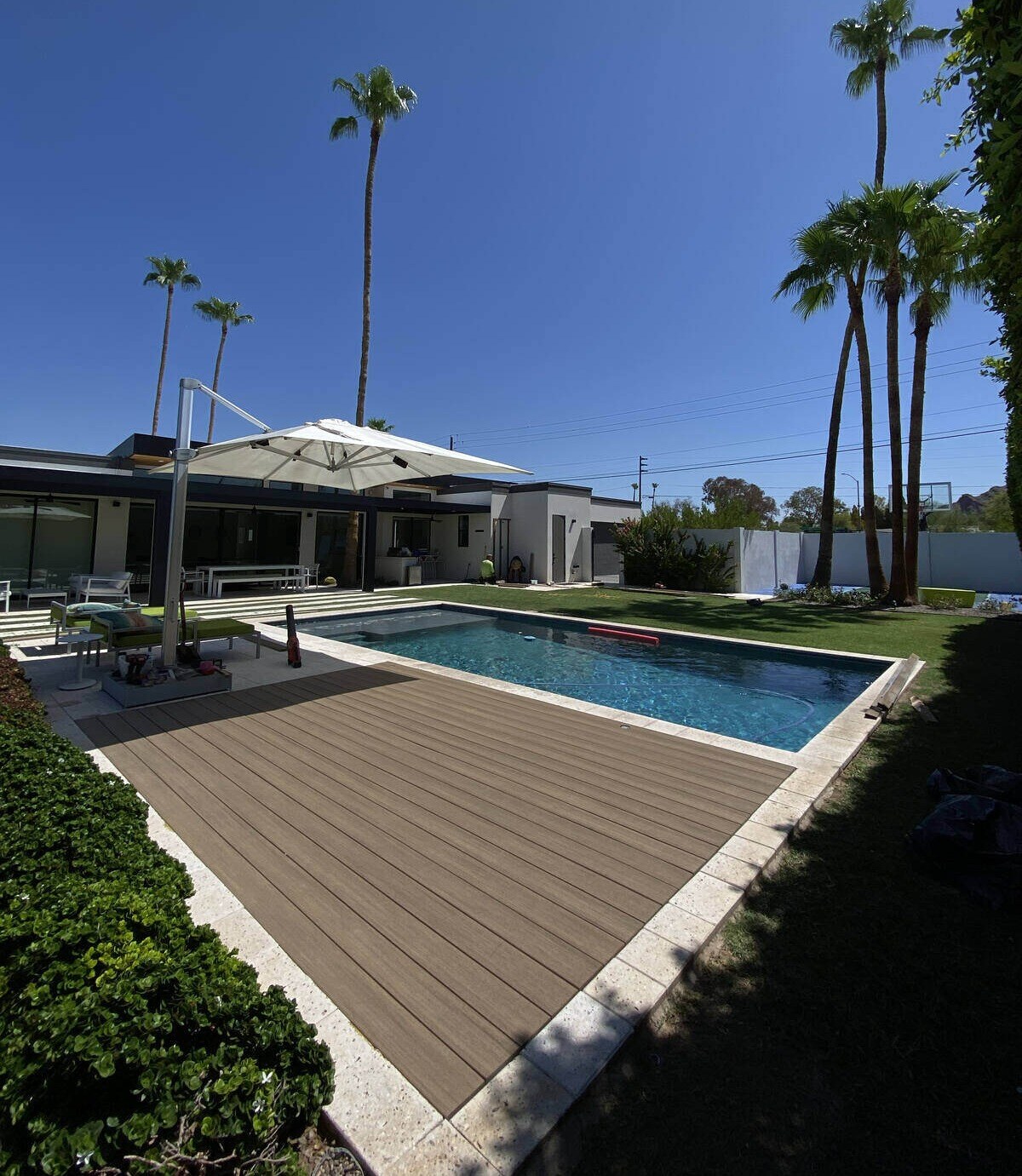 A sleek poolside deck surrounded by lush greenery and palm trees, built by Crosby Home Services in Prescott, AZ A sleek poolside deck surrounded by lush greenery and palm trees, built by Crosby Home Services in Prescott, AZ