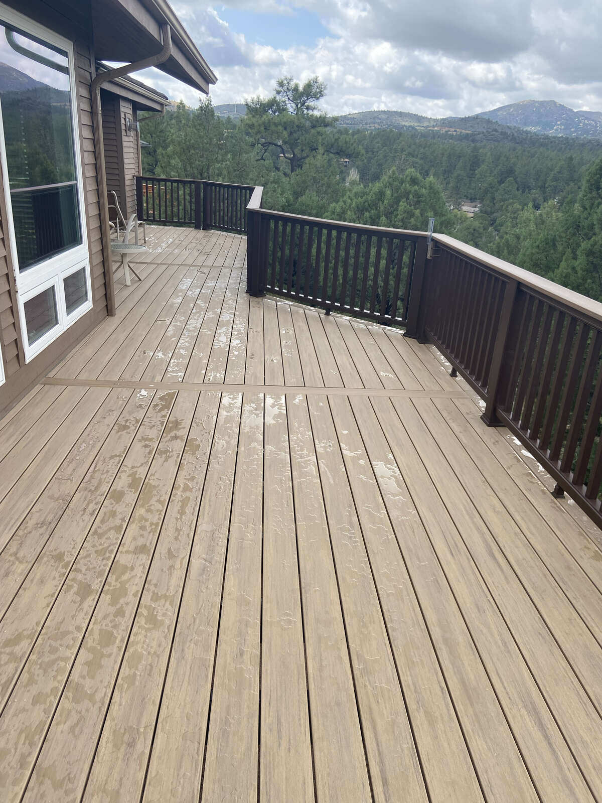 Wood-toned composite deck with contrasting railings and forest views, crafted by Crosby Home Services in Prescott, AZ