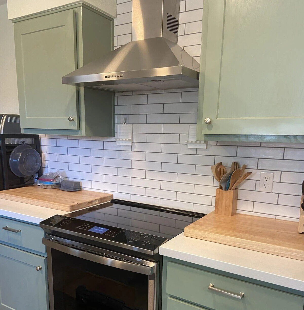 A remodeled kitchen in Prescott, AZ, with green cabinets and subway tile backsplash