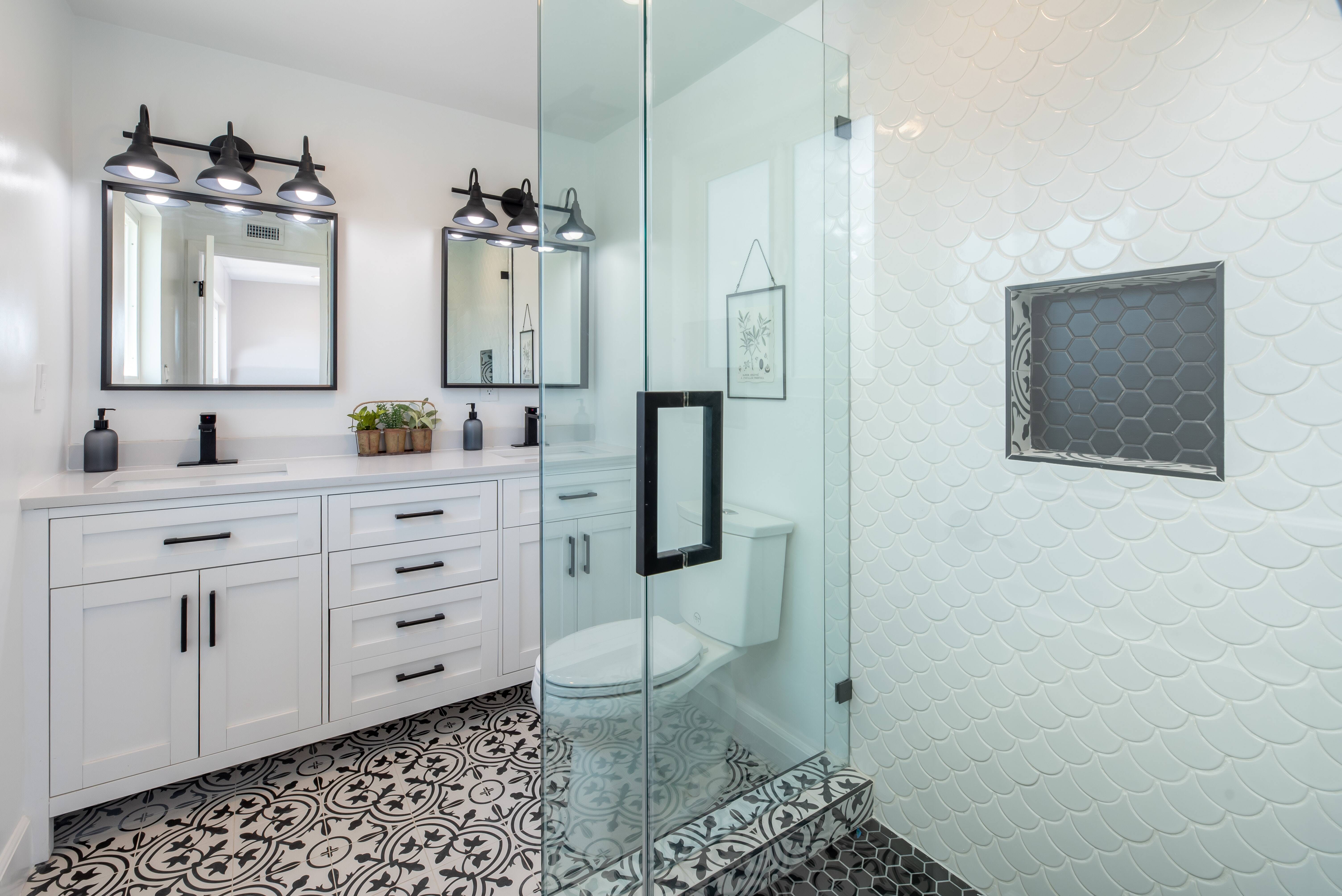 Black and white farmhouse aesthetic bathroom remodel with double sink vanity and a frameless glass shower