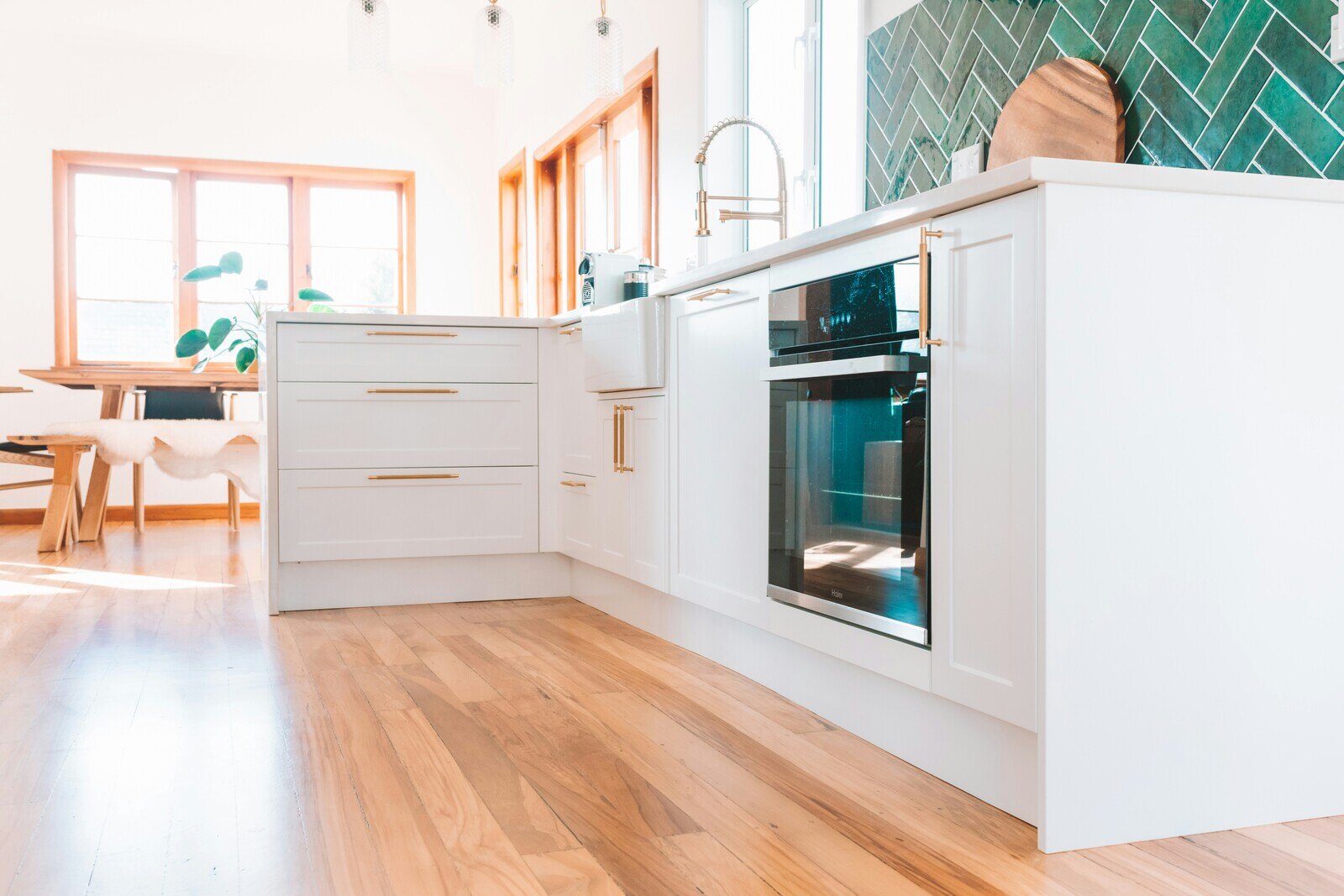 Light-filled kitchen remodel with green backsplash tiles and white cabinetry in Prescott, AZ by Crosby Home Services