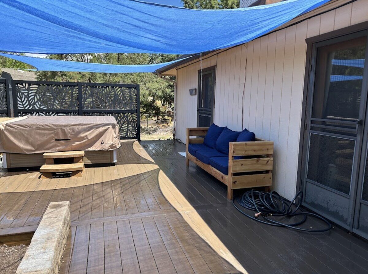 Custom wooden deck with outdoor furniture and blue shade covering, completed by Crosby Home Services in Prescott, AZ