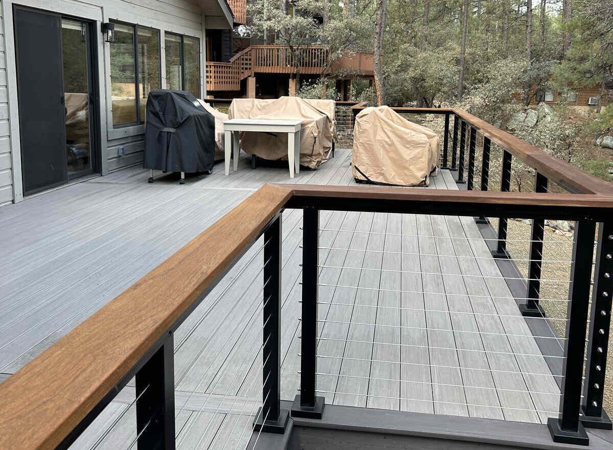 A contemporary deck with cable railing and a view of a forest, completed by Crosby Home Services in Prescott, AZ