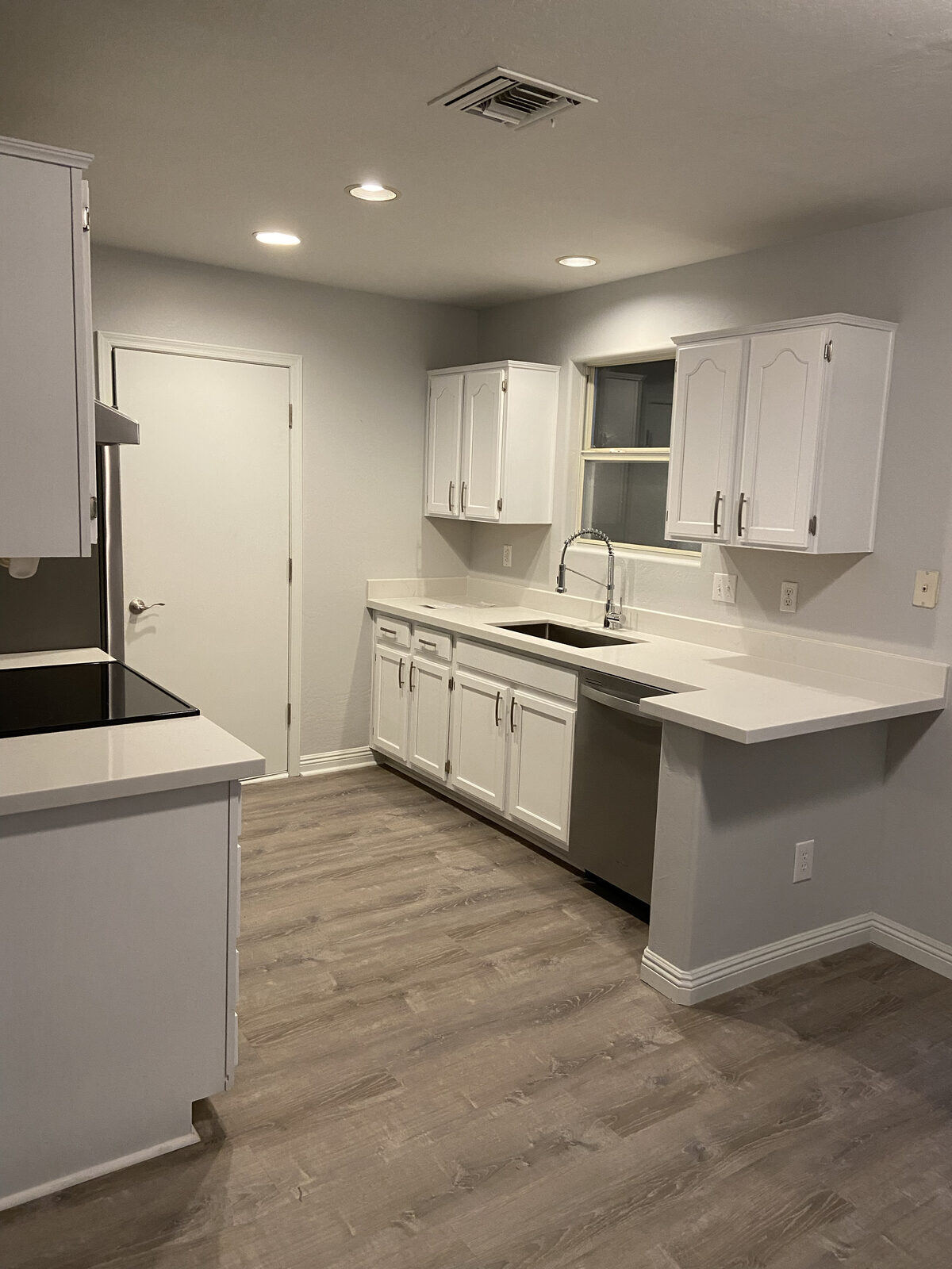 A modern white kitchen with new cabinets and wood flooring by Crosby Home Services in Prescott, AZ