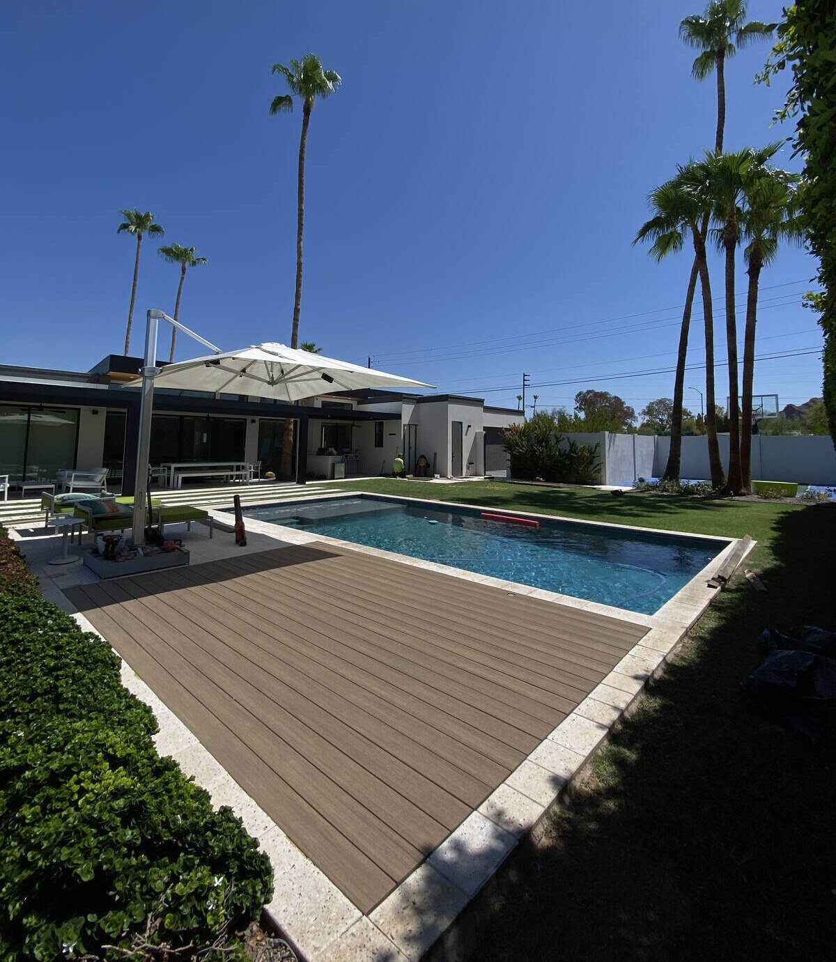 A sleek poolside deck surrounded by lush greenery and palm trees, built by Crosby Home Services in Prescott, AZ