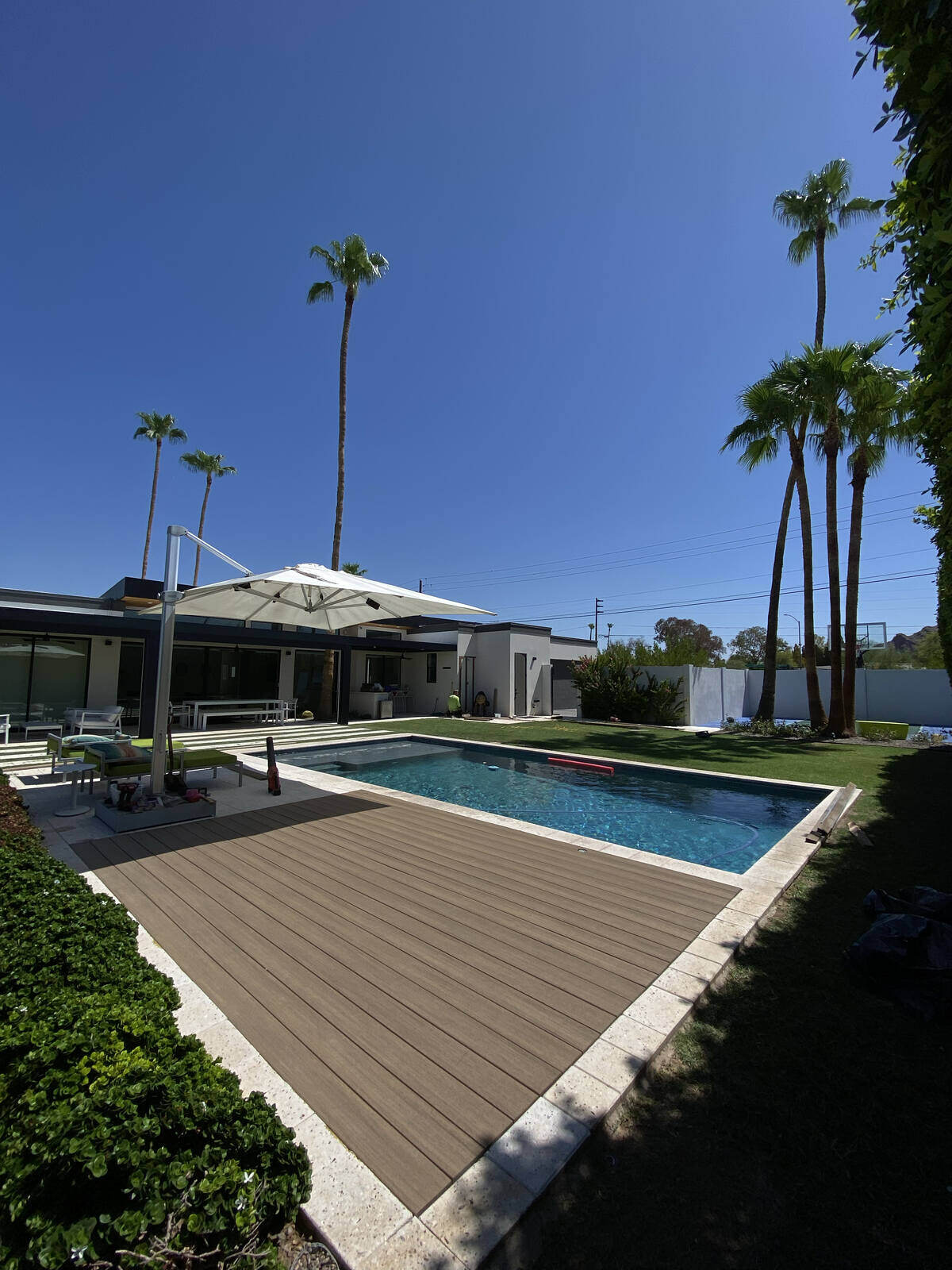 A sleek poolside deck surrounded by lush greenery 