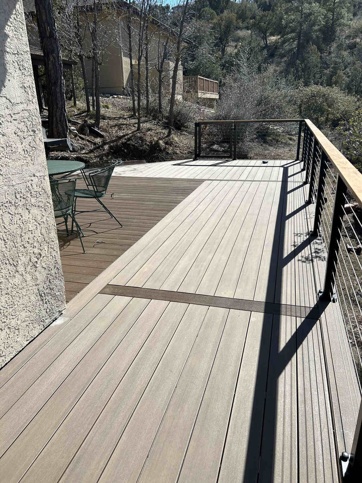 Spacious composite deck with cable railings, overlooking a lush wooded area, built by Crosby Home Services in Prescott, AZ